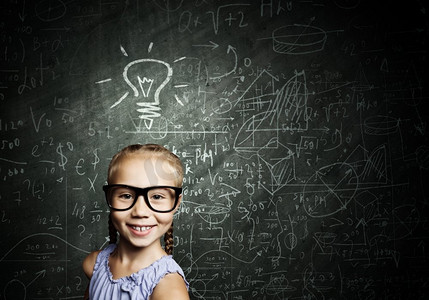 聪明的女学生。戴着红眼镜的天才女孩在黑板上写着公式