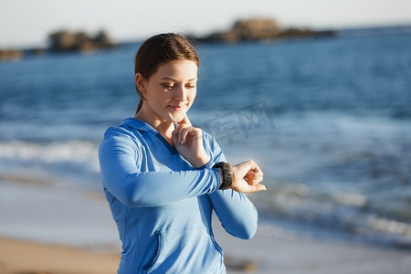 跑步者妇女与心脏率监视器跑在海滩上。有在海滩上跑的心率监视器的年轻赛跑者妇女
