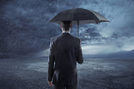 沮丧的商人拿着雨伞站着
