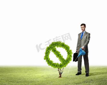 绿色植物图标摄影照片_杜绝污染。商人浇水植物形象，形状像禁令标志