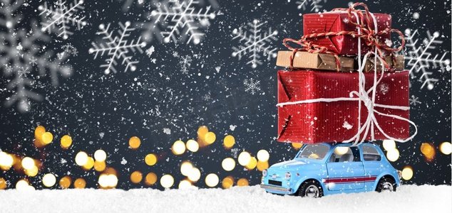 玩具礼物盒摄影照片_带有圣诞礼物的复古玩具车。蓝色复古玩具车，在节日灰色背景下递送圣诞或新年礼物