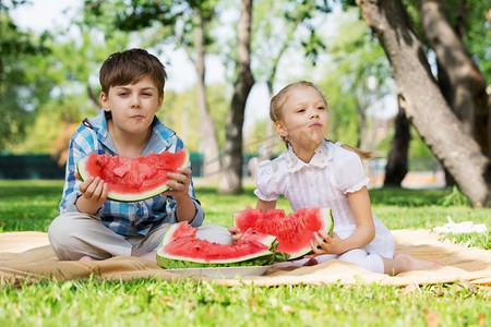 孩子们吃西瓜。公园里的可爱小朋友吃着多汁的西瓜