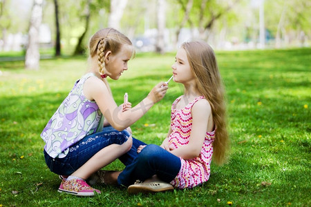 小口红摄影照片_公园里的小女孩。两个小可爱的女孩在公园草地上玩的形象
