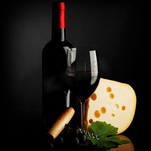 深色背景上的红酒瓶、玻璃杯、奶酪和开瓶器