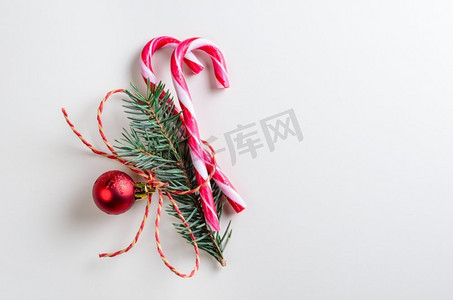 两个带冷杉树枝的糖果圆筒。圣诞或新年装饰，两个松枝糖果和灰色背景上的玩具玻璃球
