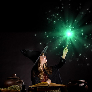变魔术可爱摄影照片_万圣节女巫。万圣节小巫婆用棍子变魔术