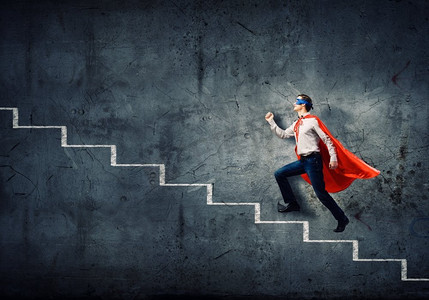 超人超人摄影照片_梯子上的超人。年轻的超人走上楼梯