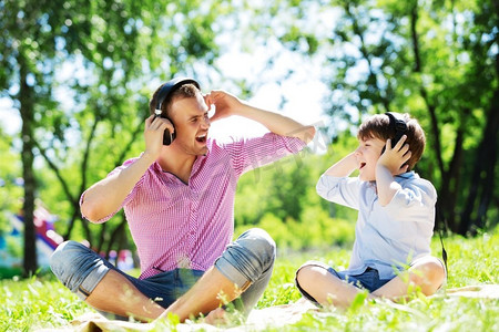 爸爸和孩子在夏令营享受音乐。周末在公园里