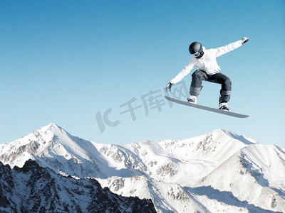 滑雪板运动员在晴朗的蓝天中跳高。单板滑雪运动