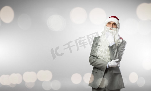 商业圣诞老人戴着圣诞老人帽子的商人，手放在下巴上