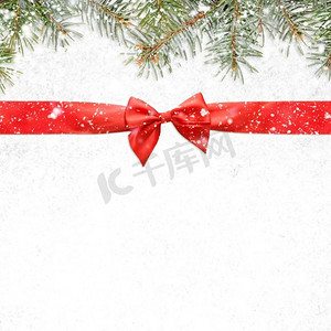 下雪的圣诞节或新年背景。圣诞卡或新年背景由红色缎带制成，雪和冷杉树枝上有蝴蝶结