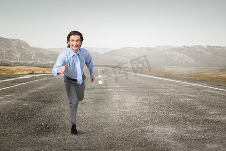 在他走向成功的路上。一名西装革履的年轻商人在户外柏油路上跑步