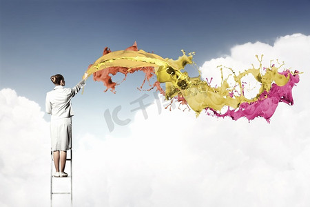 年轻女子画水花。站在梯子上画画的年轻女子用手指飞溅
