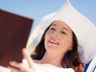 书的海洋摄影照片_阳光明媚的日子里，海滩上一位穿着白色衣服的妇女。海滩上美丽的一天