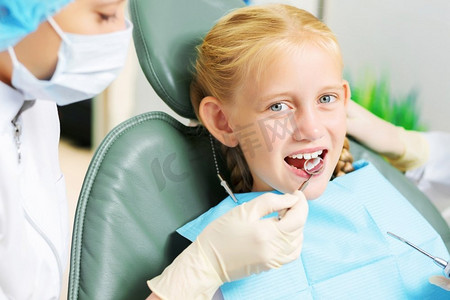 检查牙齿。坐在扶手椅上看牙医的可爱微笑的女孩