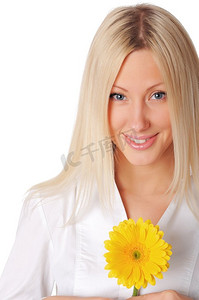 年轻的微笑金发女郎在一个白色的衬衫玩黄色的花在手中