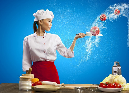 刀切水果摄影照片_亚洲女厨师用刀。亚洲女性厨师与刀切水果和蔬菜在空气中