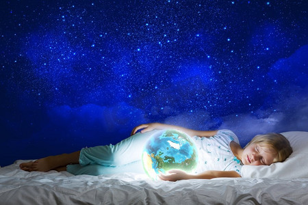晚安。女孩躺在床上，手里拿着地球。这张图片的要素由美国宇航局提供