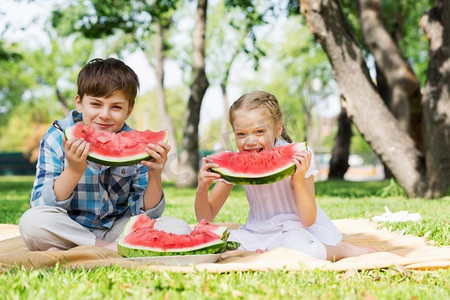 孩子们吃西瓜。公园里的可爱小朋友吃着多汁的西瓜