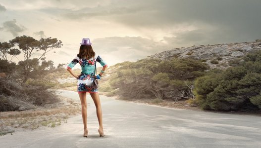 徒步旅行的概念。站在路边的年轻女子的背影