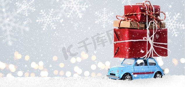 带有圣诞礼物的复古玩具车。蓝色复古玩具车，在节日灰色背景下递送圣诞或新年礼物