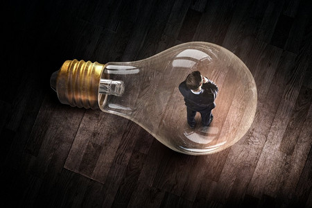 电灯泡里的人聪明的商人在玻璃灯泡作为头脑风暴的概念