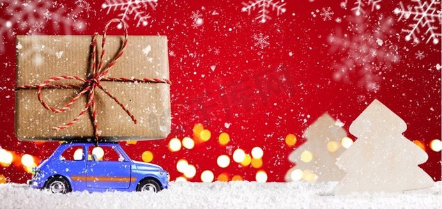 复古玩具车与圣诞礼物。蓝色减速火箭玩具车提供在节日红色背景的圣诞节或新年礼物