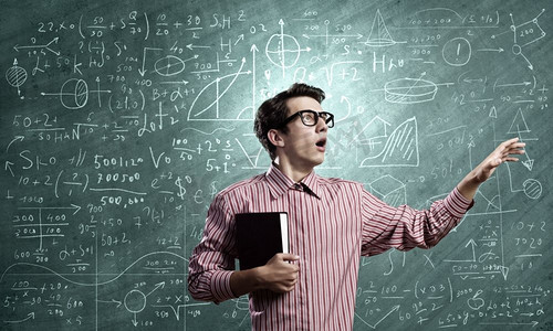 有趣的科学家。戴眼镜的年轻滑稽男子靠在粉笔黑板上