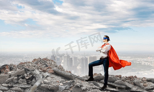 坚定的超人自信超人在斗篷和面具站在废墟上