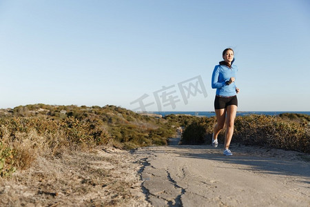 运动跑步者在海滩上慢跑锻炼。健康的女性健身模特沿着海洋慢跑