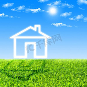 绿地产摄影照片_云彩的房子在蓝天反对绿草的背景.
