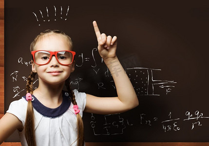 儿童数学摄影照片_神童。戴眼镜的可爱女学生站在黑板前