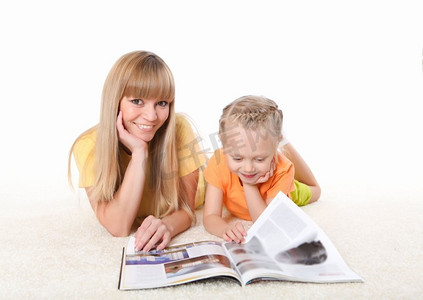 年轻的母亲在地毯上给她的小女儿读书