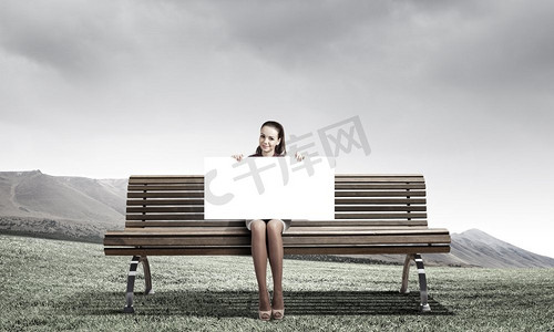 魏国献礼摄影照片_献礼的女孩。坐在板凳上的年轻女子举着白色的横幅