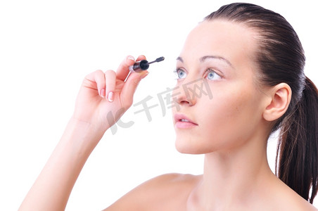 年轻迷人的性感女人在脸上涂抹化妆品，斜视着白色皮肤