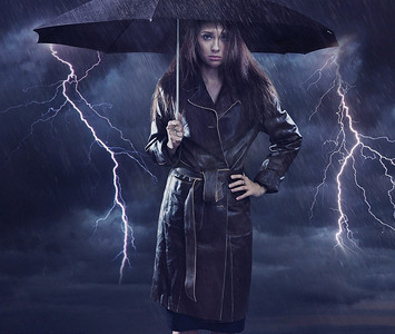 杂志创意摄影照片_单身女子穿着外套撑着伞。恶劣天气的创意之声