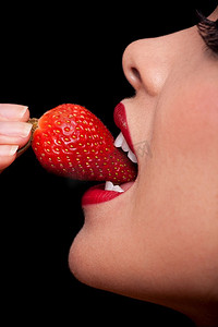 一张美丽的女性嘴巴吃着新鲜草莓的微距特写