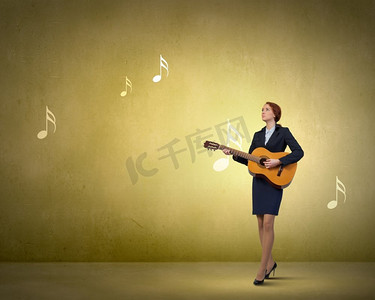 女商人玩原声吉他。愉快的女实业家演奏木吉他在彩色背景