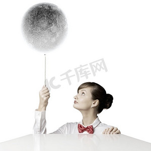 月球星球摄影照片_有月亮的女人。年轻女子手持月球星球颜色的气球