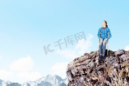 隔离的概念。一位穿着休闲服装的年轻女子坐在岩石上