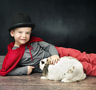 神奇的宝贝摄影照片_魔术师小男孩抚摸一只兔子