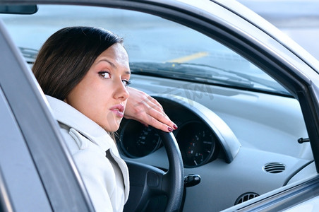美丽性感的女人把她的头放在方向盘上,回头看相机汽车内饰雨刷