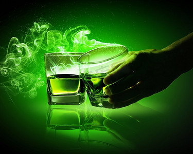 两杯绿色苦艾酒。手持两杯带烟的绿色苦艾酒中的一杯