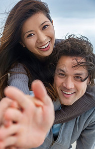 年轻的亚洲男人和女人浪漫的夫妇，男孩和女孩微笑与完美的牙齿玩猪背在海滩和达到相机