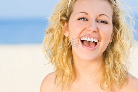 一位性感美丽的年轻金发女子在海滩上发出自然的大笑