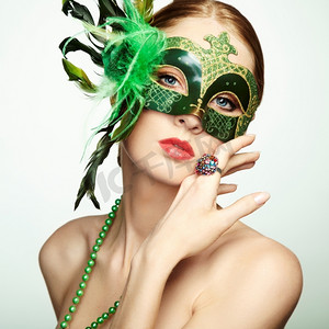 神秘面具人摄影照片_戴着绿色神秘威尼斯面具的美丽年轻女子