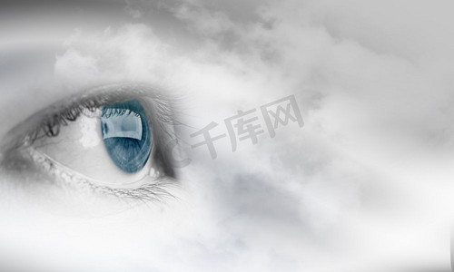 眼睛健康女性蓝眼睛在多云的天空背景 