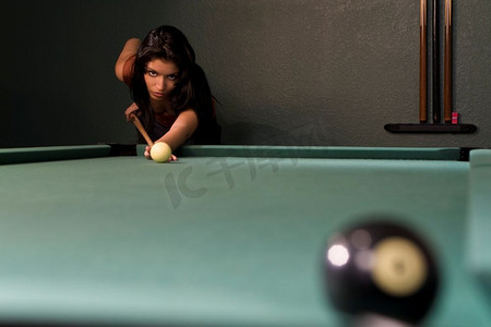 一个性感和美丽的西班牙裔女子打台球和即将沉没的八球