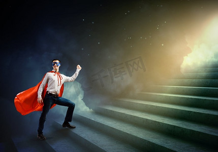 行走的超级英雄年轻自信超人面具和斗篷走在梯子上