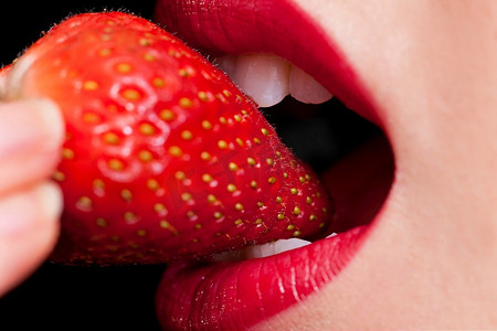张牙舞爪狮子摄影照片_一张美丽的女性嘴巴吃着新鲜草莓的微距特写